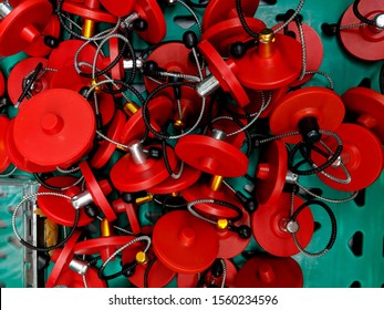 A Pile Of Bright Red, Plastic And Wire, Electronic Article Surveillance Security Tags In A Green Crate. A Technological Method For Preventing Shoplifting From Retail Stores Or Theft From Libraries