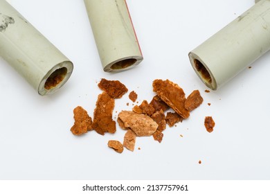 A pile of brown debris (lime, rust and scale) from old polypropylene water pipes on a white background. The concept of pipe replacement due to poor water supply. Selective focus on trash.