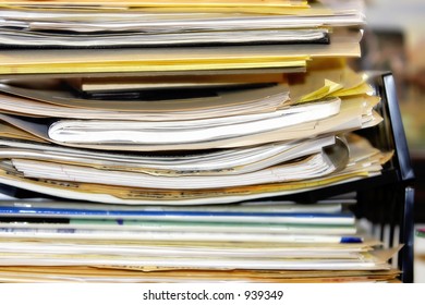 Pile of business/healthcare paperwork and/or forms stacked in an overflowing inbox.