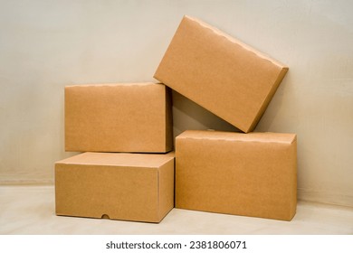 A pile of cardboard boxes arranged in a stack on a beige colored background