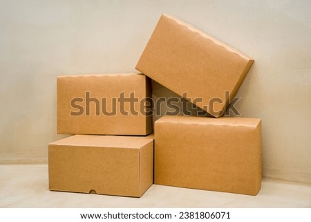 A pile of cardboard boxes arranged in a stack on a beige colored background