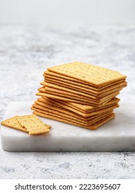 Pile Of Cheese Crackers On A White Marble Cutting Board On A White Background