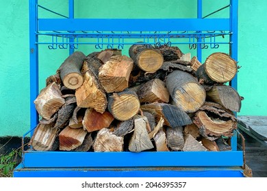 Pile of chopped firewood stacked in woodpile for heating in winter or for fireplace. Near by wall of residential building. Close-up. Outdoors.