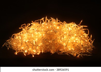 Pile of Christmas tree lights against a black background.