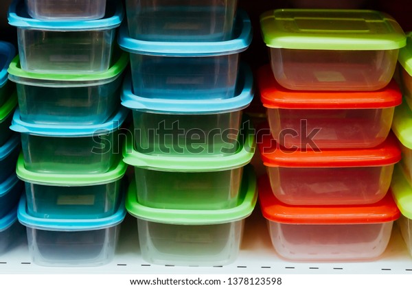 A pile of clear plastic\
containers. Transparent organising boxes for storage with colorful\
covers.