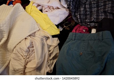 Pile of clothes. Closedup of used clothes on sale in a flea market. Different colored clothes for background. Mixed up dresses such as shirts, jeans, jackets, scarf, pants, and other used clothes.