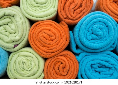 Pile Of Colorful Blankets Made From Fleece, All Rolled Up.