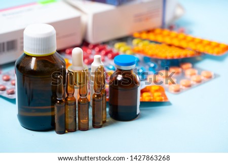 Pile of colorful medical pills and bottles on blue background. Druga and antibiotic prescription for treatment medication