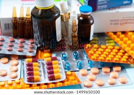 Pile of colorful medical pills and bottles on blue background. Druga and antibiotic prescription for treatment medication