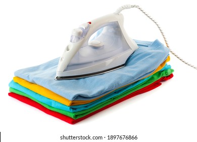 A Pile Of Colorful T Shirts With An Iron On Top. Studio Photo Isolated On White Background.