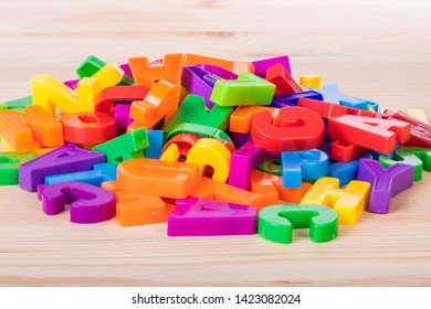 A Pile Of Coloured Magnetic Letters Over A School Wooden Table