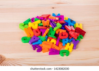 A Pile Of Coloured Magnetic Letters Over A School Wooden Table