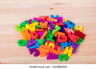 A Pile Of Coloured Magnetic Letters Over A School Wooden Table