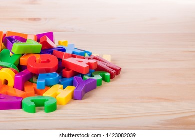 A Pile Of Coloured Magnetic Letters Over A School Wooden Table