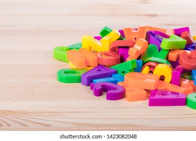 A Pile Of Coloured Magnetic Letters Over A School Wooden Table