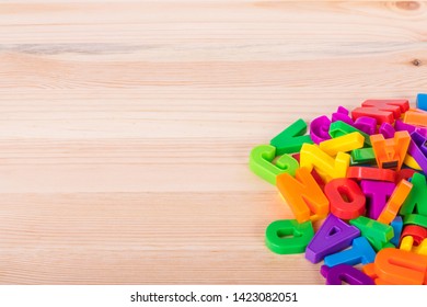 A Pile Of Coloured Magnetic Letters Over A School Wooden Table