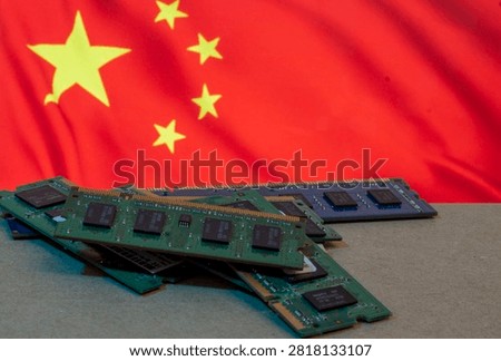 A pile of computer RAM memory sticks and electronic components set against the blurred flag of China, representing technology production, the semiconductor industry, and manufacturing in China