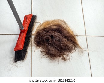 A Pile Of Cut Hair On The Barber Shop Floor Next To A Broom.