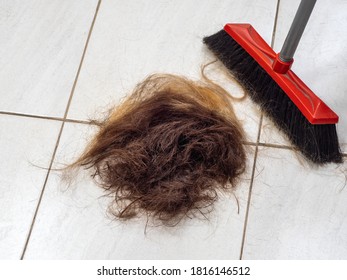 A Pile Of Cut Hair On The Barber Shop Floor Next To A Broom.