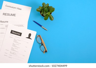 Pile of cv papers application form on a blue desktop.Top view