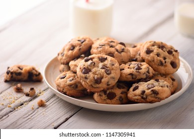 Pile of Delicious Chocolate Chip Cookies on a White Plate with Milk Bottles