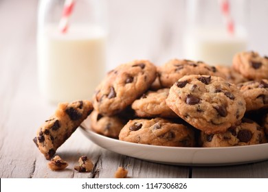 Pile of Delicious Chocolate Chip Cookies on a White Plate with Milk Bottles - Powered by Shutterstock