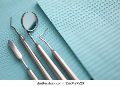 Pile of dentist tools lying at green tissue ready to be used close-up - Powered by Shutterstock