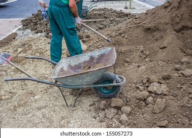 Pile of dirt, using several wheel barrows, workers shoveled and dumped, shoveled and dumped, transporting wheel-barrow-fulls at a residential construction site doing preparation for lawns