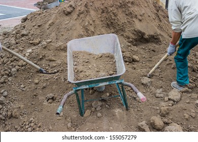 Pile of dirt, using several wheel barrows, workers shoveled and dumped, shoveled and dumped, transporting wheel-barrow-fulls at a residential construction site doing preparation for lawns 