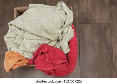 
Pile Of Dirty Clothes Multicolored Towels In A Box For Washing On A Background Of Brown Tiles. Clothes Is Prepared For Washing. Dirty Clothes In The Basket