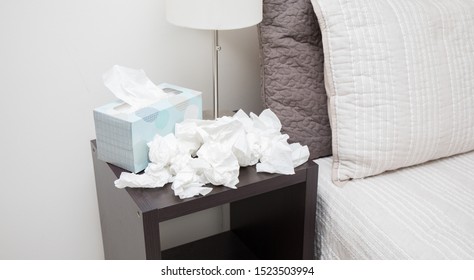 A Pile Of Dirty, Used, And Crumpled Up Tissues On A Nightstand.