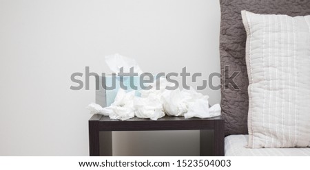 A pile of dirty, used, and crumpled up tissues on a nightstand.