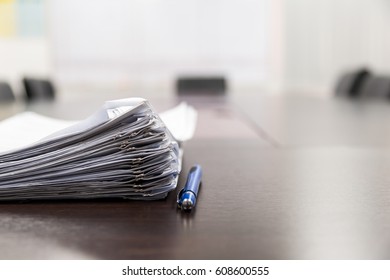 Pile Of Documents And Blue Pen On The Meeting Table With Blurred Background. Conceptual Job Interview.