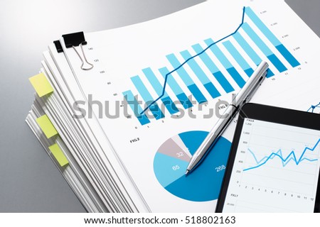 Pile of documents, smart phone and pen on gray reflection background. Many graphs and charts. Concept image of data gathering.
