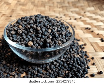 Pile of dried black pepper in a glass bowl in closeup photo. A cooking spice or food ingredient that has a spicy taste and distinctive aroma - Powered by Shutterstock