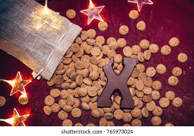 Pile of Dutch baked goods coming out of a burlap bag, traditional to five december holiday in the Netherlands. Chocolate letter on it  and string lights shaped like stars.  - Powered by Shutterstock