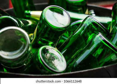 Pile Of Empty Beer, Green Glass Bottles, Invert Bottom Up Collected In Steel Bin For Recycle Selling. Container Industry Or Waste Management Concept.