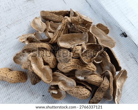 A pile of empty peanut shells or groundnut husks on a textured white surface. Detailed close-up of organic waste, natural texture, and agriculture byproduct.