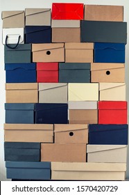 Pile Of Evenly Folded Shoe Boxes Against A White Wall. Seasonal Sales And Discounts. Vertical Photo.