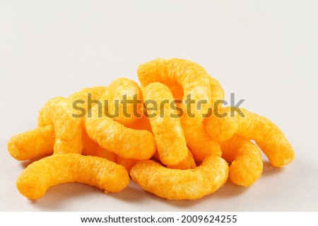 Pile of extruded cheese puffs isolated on white.
