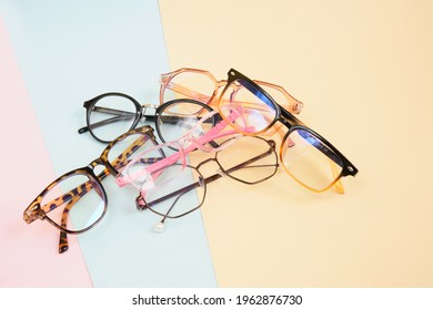 pile of fashionable trendy eyes glasses for correcting vision on a colorful background, a geometric background from pastel paper