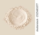 A pile of fine, beige powder on a neutral background. The powder appears soft and textured, with a circular pattern in the center. Beige powder, fine texture, neutral tone.