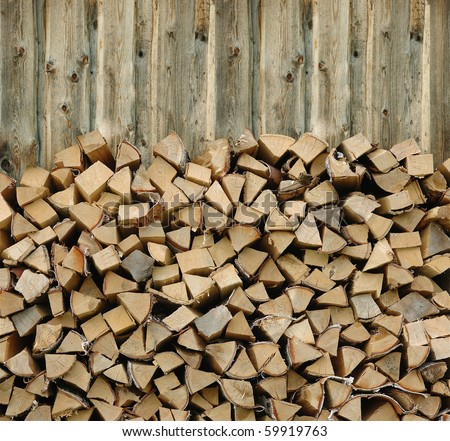 Pile of firewood against old wooden fence