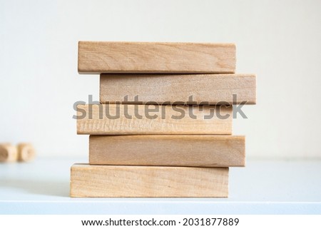 A pile of five wooden blocks on the soft white background.