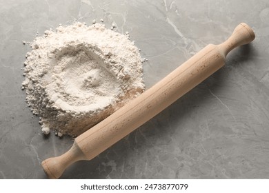 Pile of flour and rolling pin on grey marble table, top view