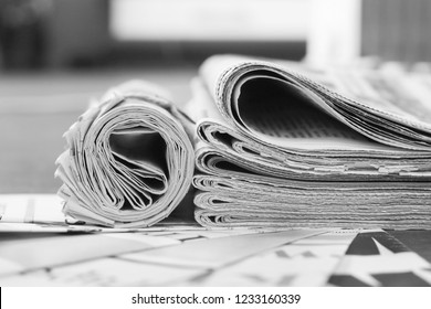 Pile of fresh morning newspapers on pages with headlines and articles at the office. Business news  in daily papers. Folded and stacked journals with selective focus       