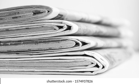 Pile of fresh morning newspapers on the table at office. Latest financial and business news in daily paper. Pages with information (headlines, articles, photos, text). Folded and stacked journals      - Shutterstock ID 1574937826