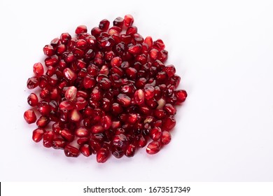 Pile Of Fresh Pomegranate Seeds Isolated On White. Red Healthy Fruit. Top View. Food And Healthy Lifestyle Concept. Copy Space.
