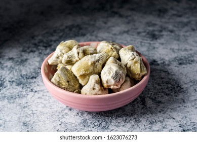 a pile of frozen artichoke hearts in a light pink ceramic bowl, on a table or countertop