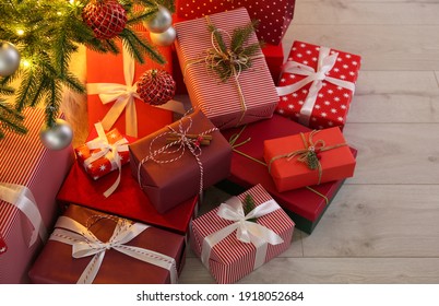 Pile of gift boxes near Christmas tree on floor